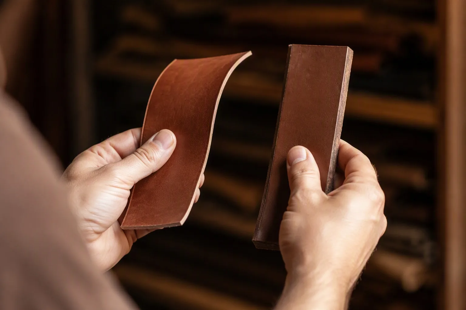 Hands flexing a thin supple leather panel against a thick stiff one