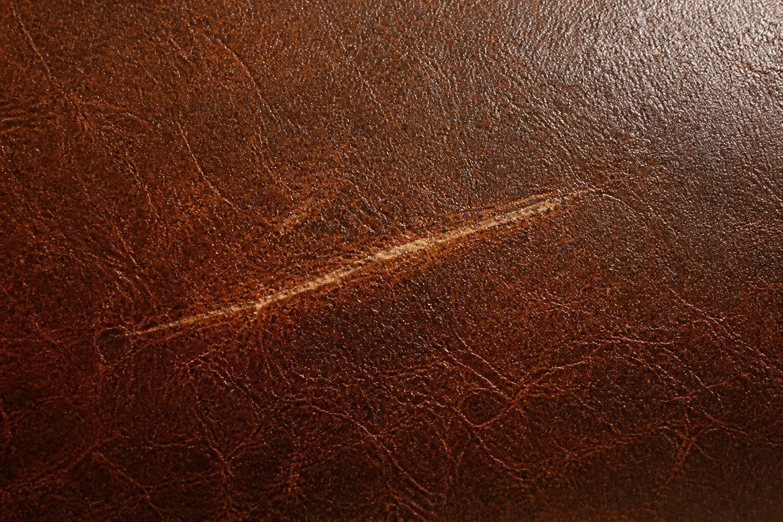 A light scratch on pull-up leather showing the characteristic lighter tone that fades back over time