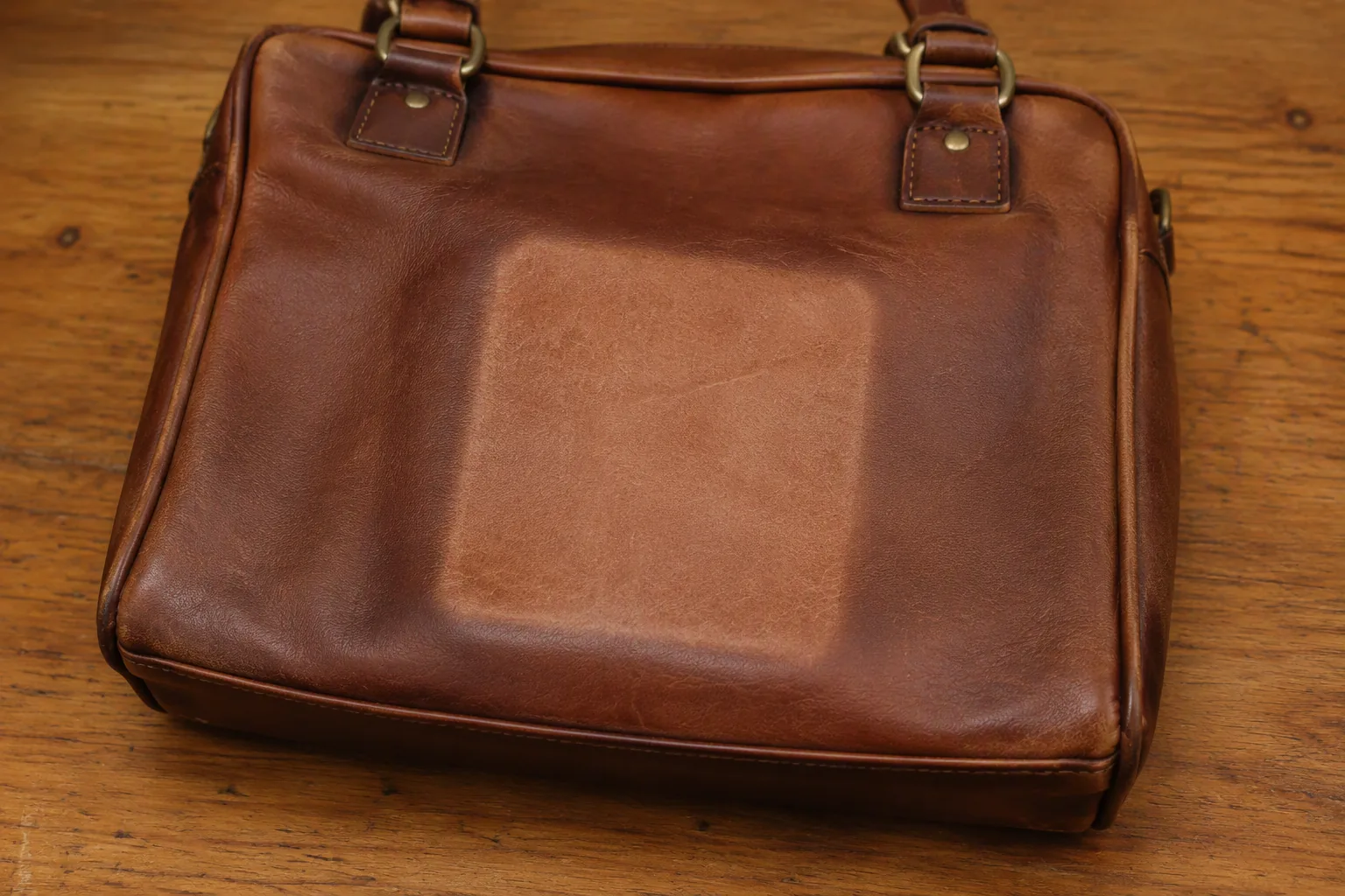 A leather bag with a lighter patch where a label covered the surface