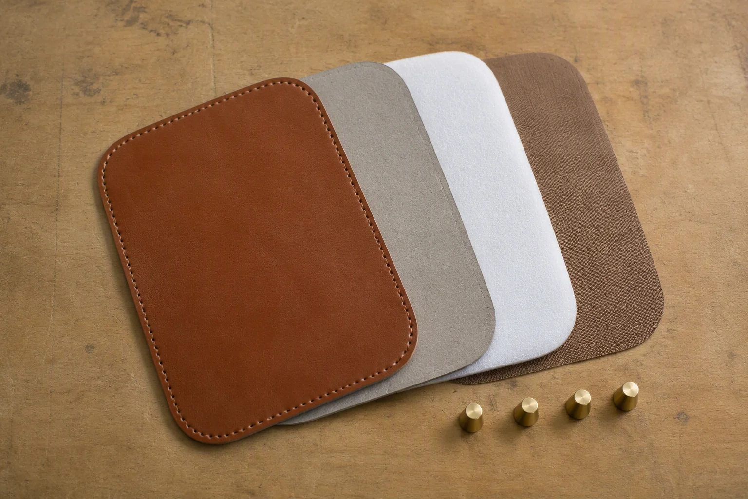 Bag base components laid out on a workbench: leather, board, padding, lining and feet