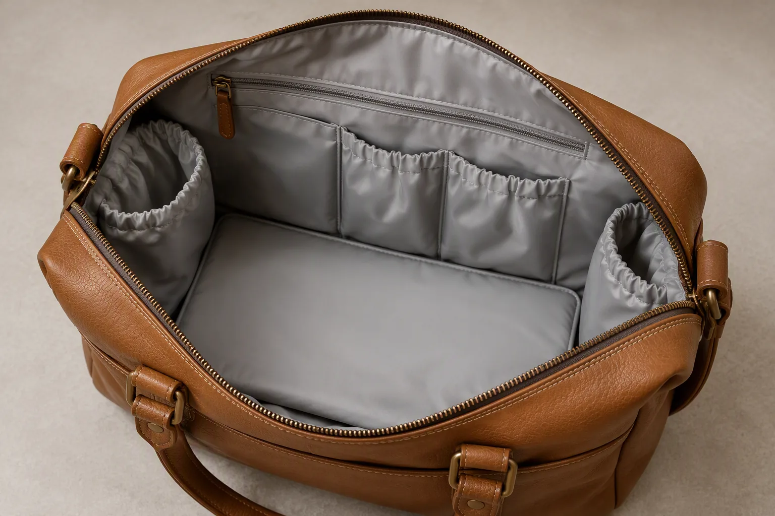The open interior of a leather diaper bag showing wipe-clean lining and pockets