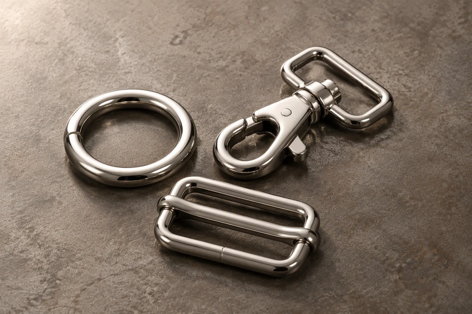 Three plated metal bag fittings resting on a bench
