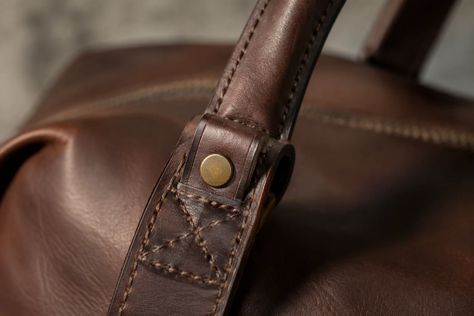 A leather shoulder bag hanging from a plain wooden shoulder form